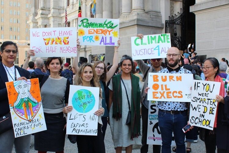 Group of climate change activists posing with signs in front a municipal building.